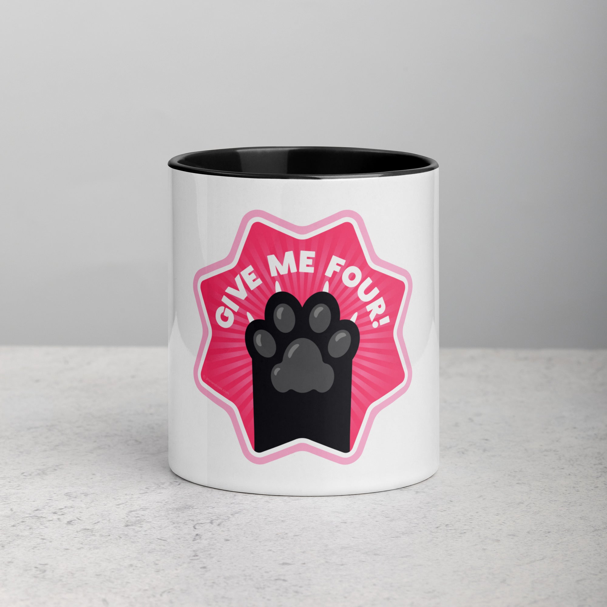front facing image of a white mug with black interior and handle. Mug has image of a black cats paw on a pink 8 sided star with the text 'give me four'